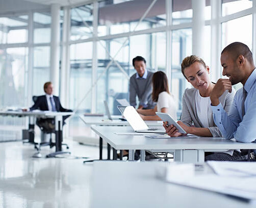 Business colleagues discussing over digital tablet at desk in office